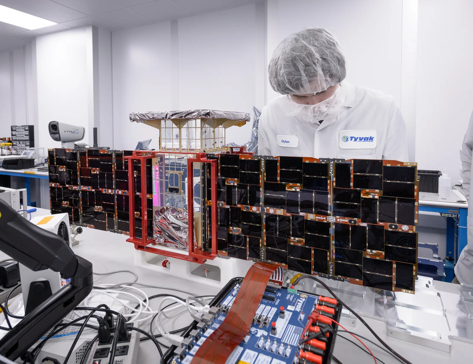 An engineer installs solar panels on the CAPSTONE CubeSat during assembly in a clean room