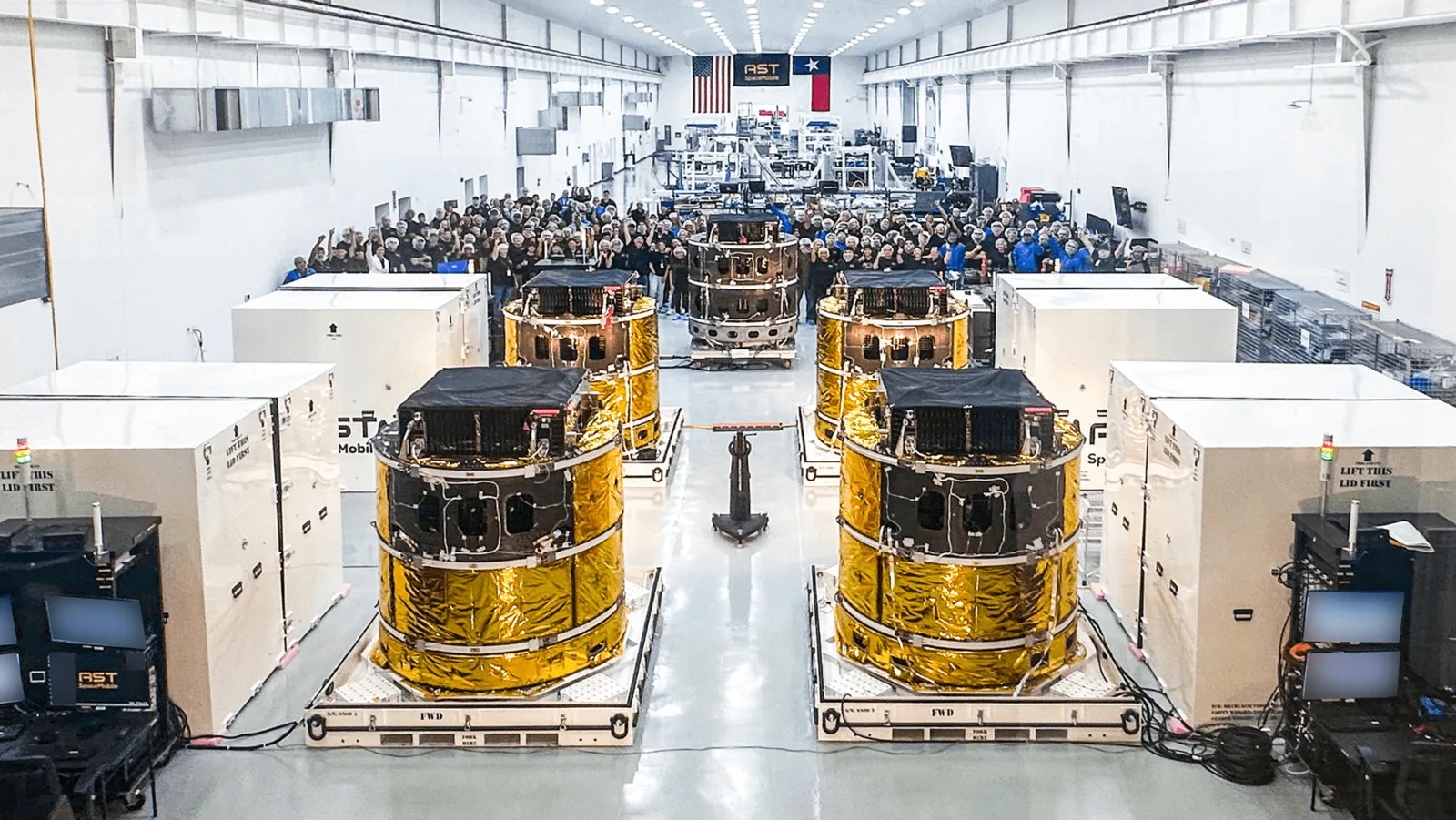 Five finished BlueBird satellites, stowed with their gold-wrapped antenna arrays folded, on the factory floor at AST SpaceMobile's Midland, Texas site