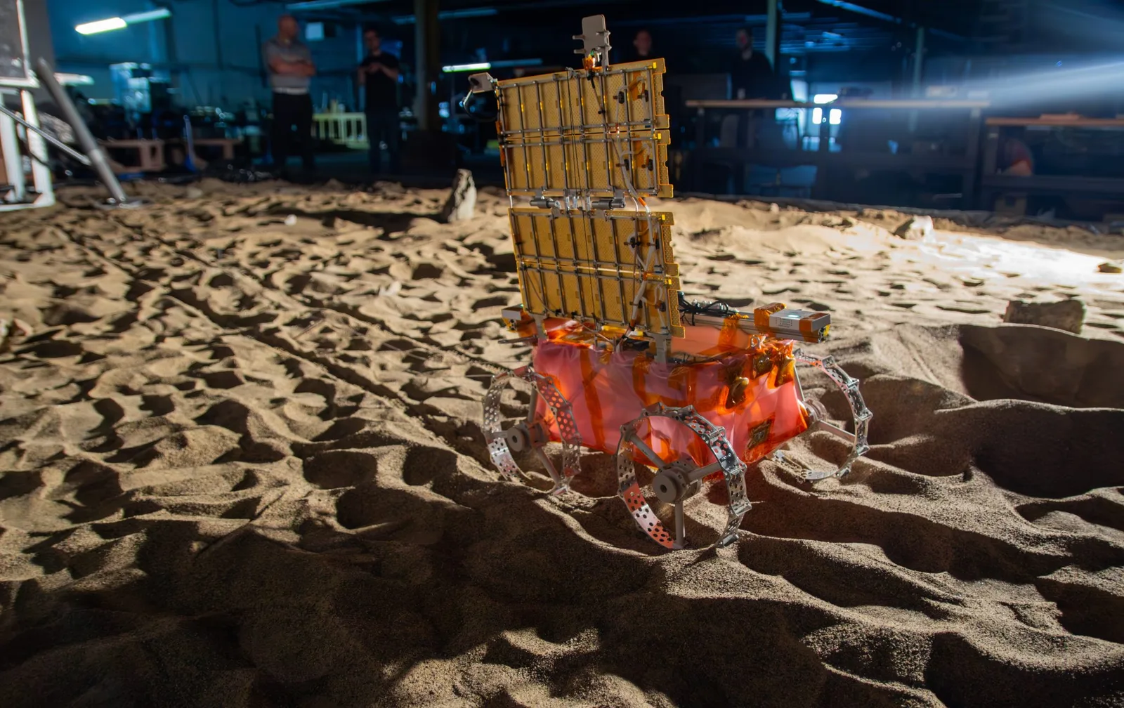Astrobotic's LunaGrid-Lite rover with its vertical solar panel driving across simulated lunar soil during a deployment test