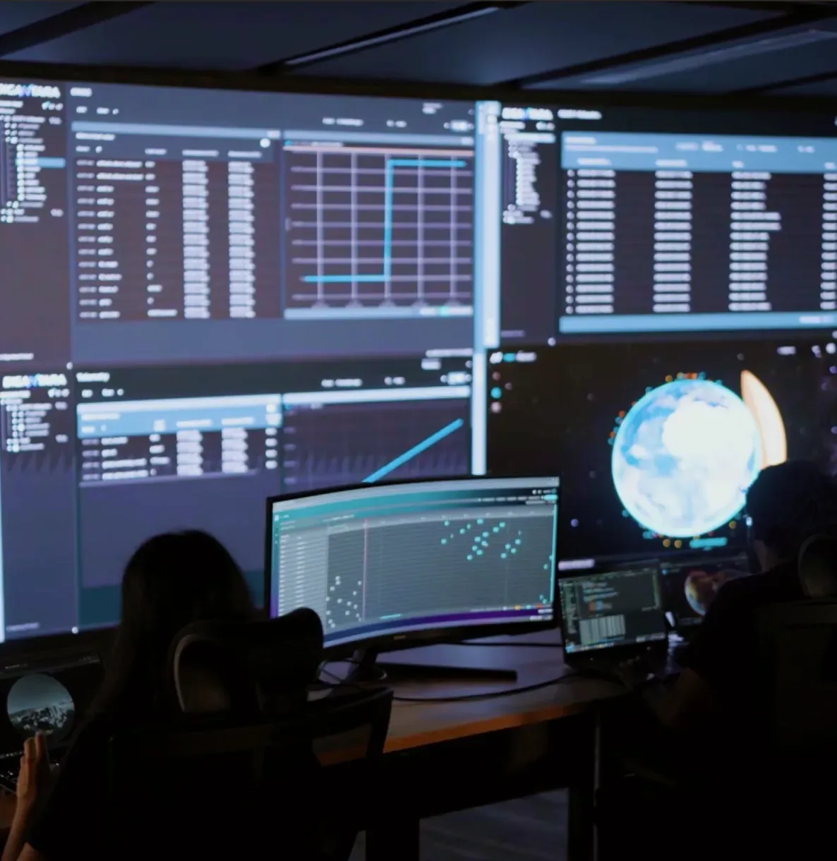 Operators in a dark control room watching large screens that show Space-MAP tables, charts and a globe of tracked objects