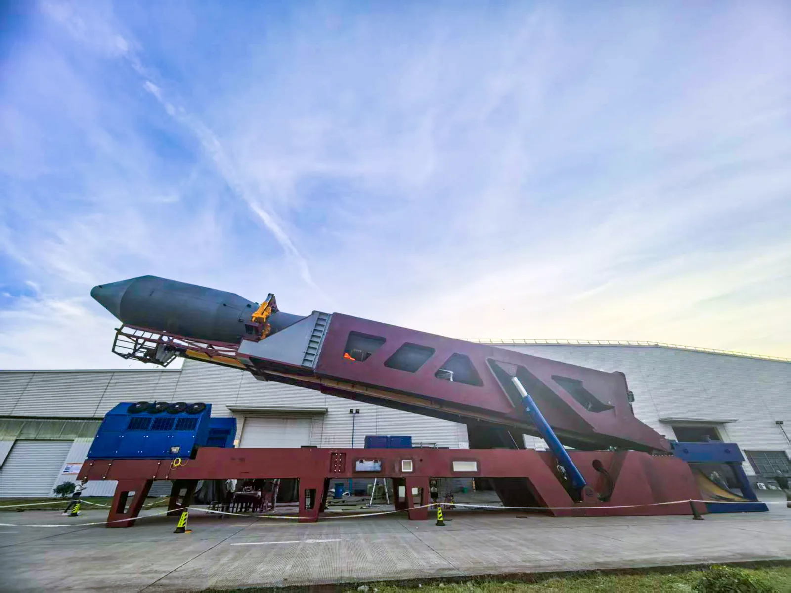 Ceres-2 rocket lying on its red transporter-erector outside an assembly building