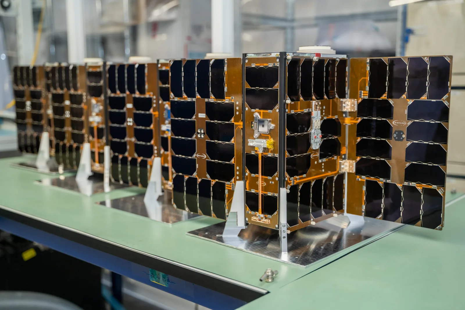 Four Kleos Observer mission cubesats with solar panels lined up on a clean-room bench