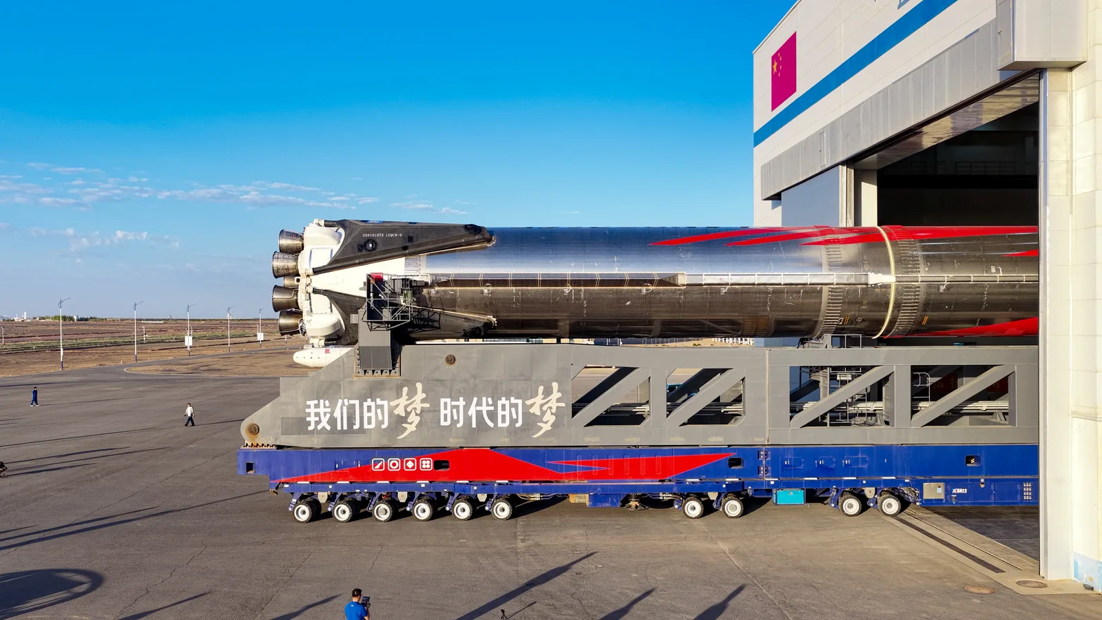 Zhuque-3 stainless-steel rocket lying horizontally on its transporter outside the assembly building