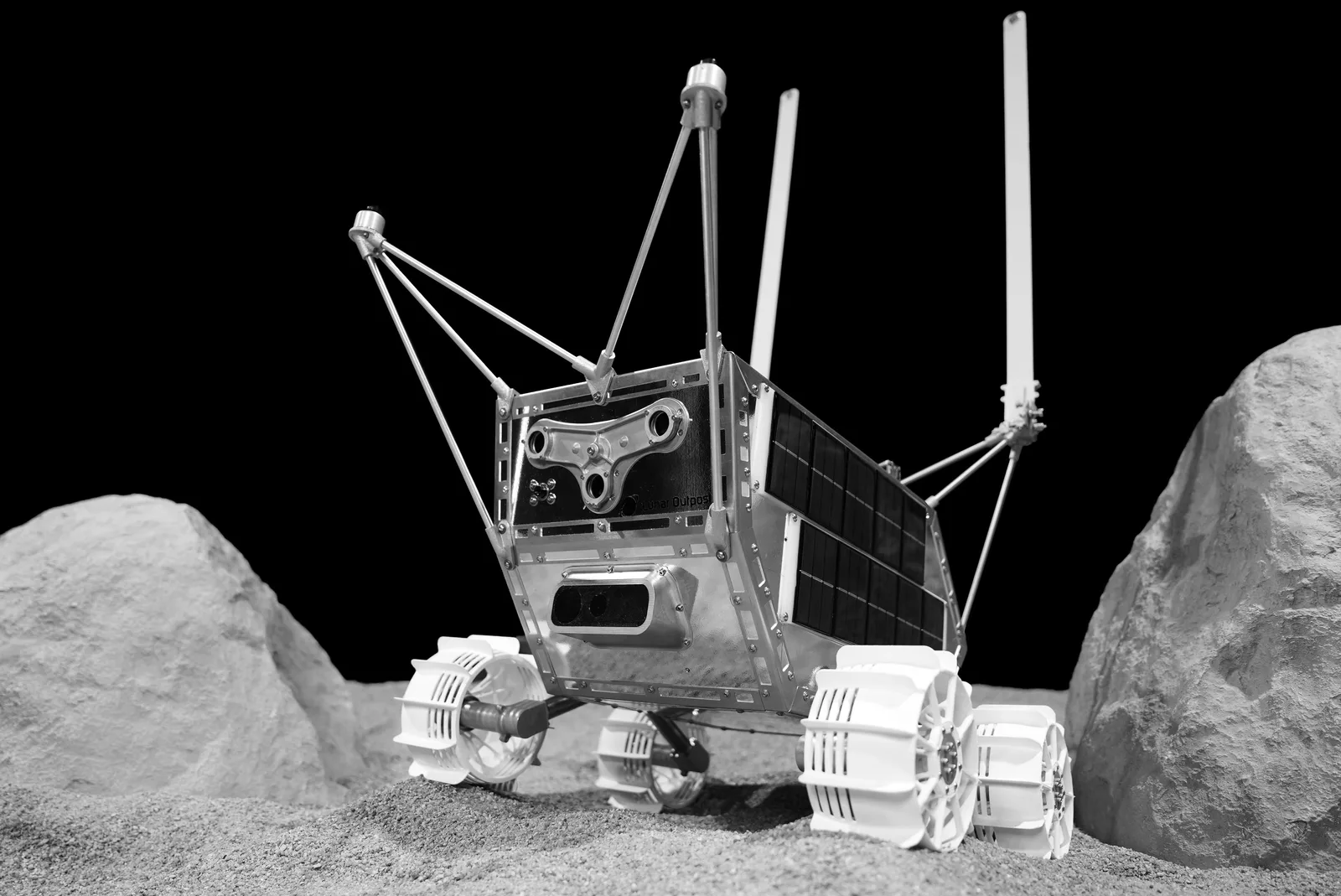 Lunar Outpost MAPP rover with raised solar panel and antennas on simulated lunar soil among boulders