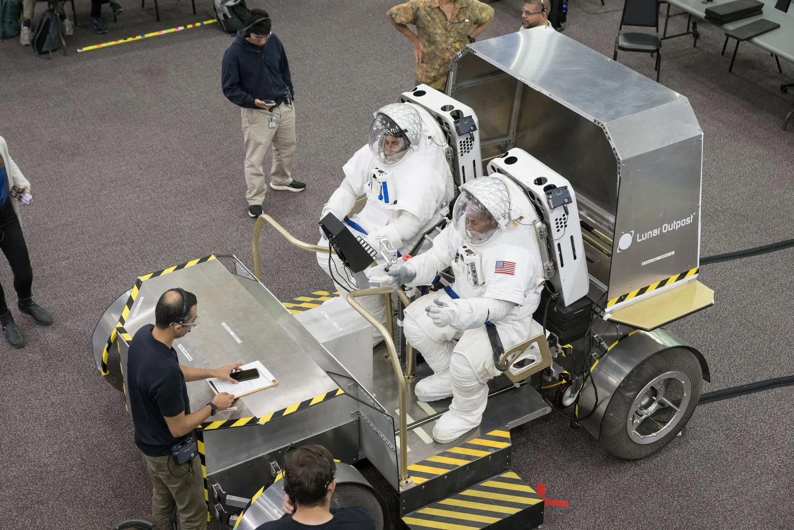 Astronauts in spacesuits seated in a Lunar Outpost Pegasus lunar terrain vehicle prototype during crewed testing