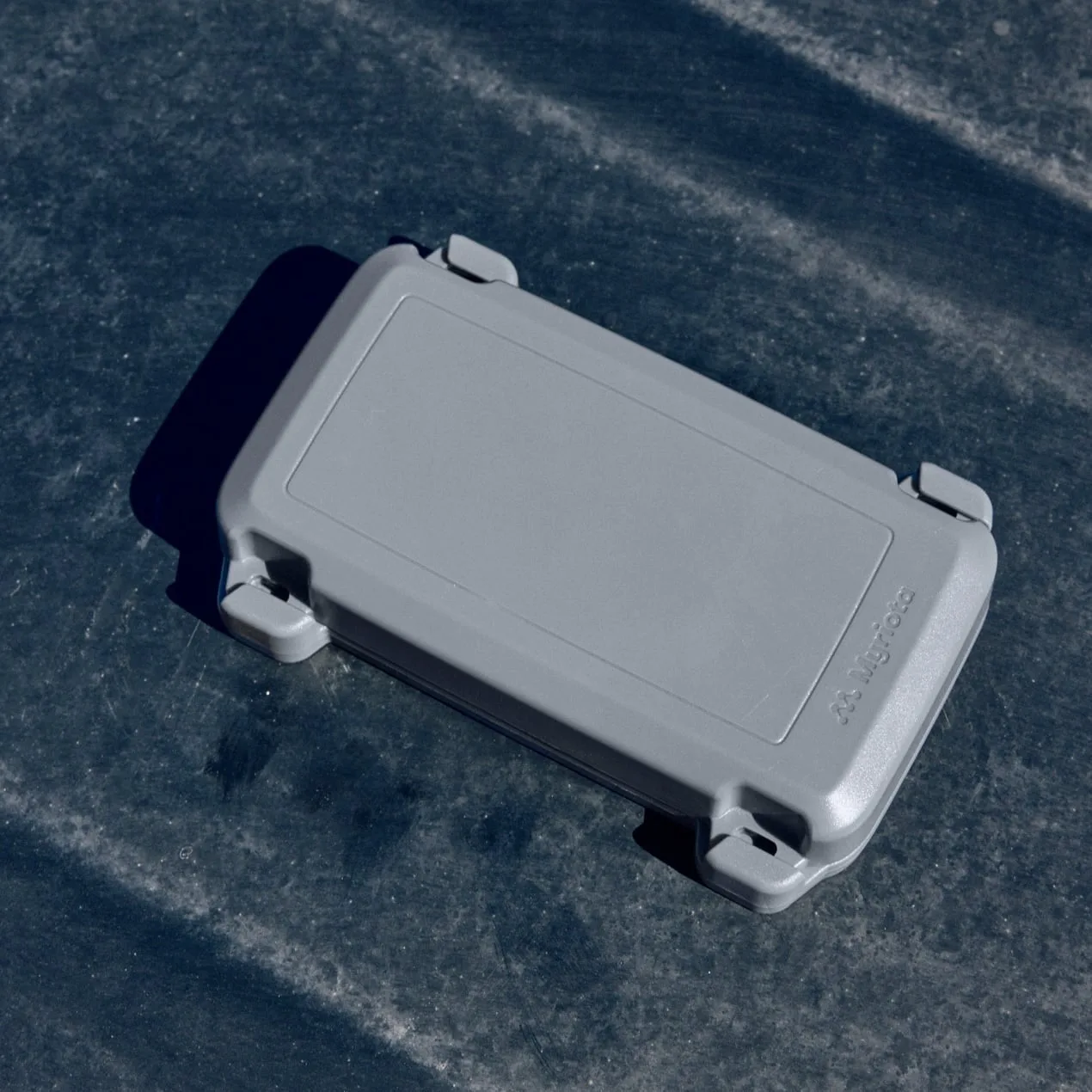 Myriota AssetHawk satellite asset tracker, a gray rugged device mounted on a surface