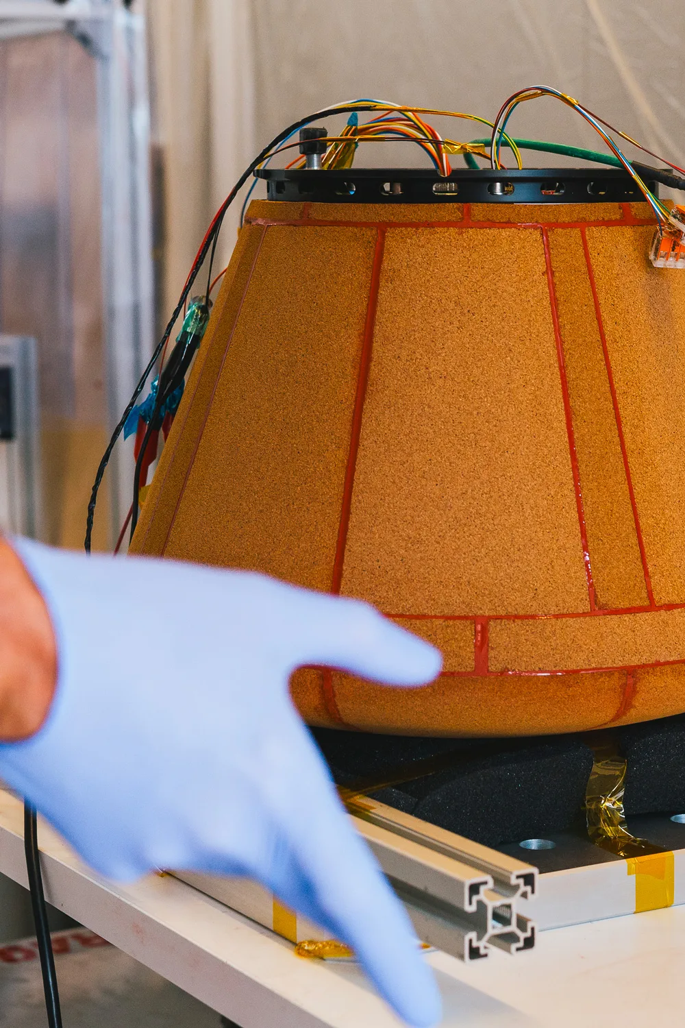 The KID reentry capsule, with its orange heat shield, on a lab bench