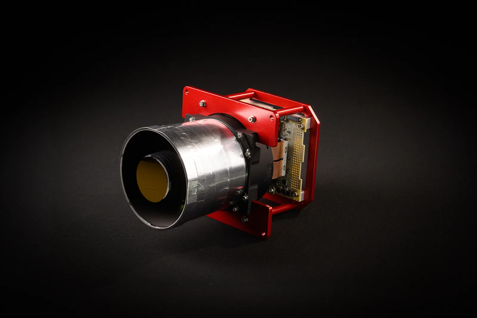 Simera Sense HyperScape100 hyperspectral camera, a silver lens barrel on a red mounting frame, against a black background