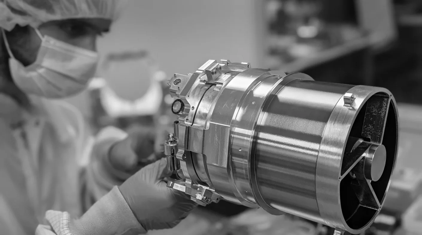 Black-and-white photo of a technician in a cleanroom holding a Skyloom optical communication terminal