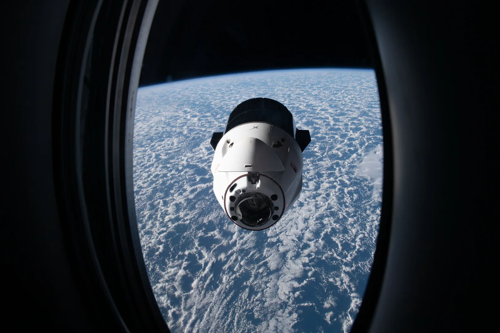 A SpaceX Dragon spacecraft approaching the International Space Station above the South Atlantic, seen through a window of the Crew Dragon Freedom, July 2022