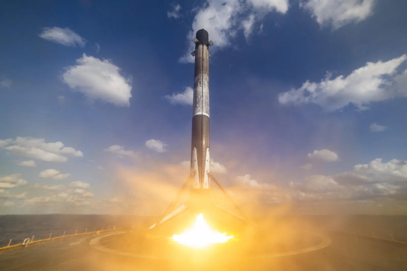 A Falcon 9 first-stage booster firing its engine as it lands on a SpaceX droneship at sea after a Starlink launch