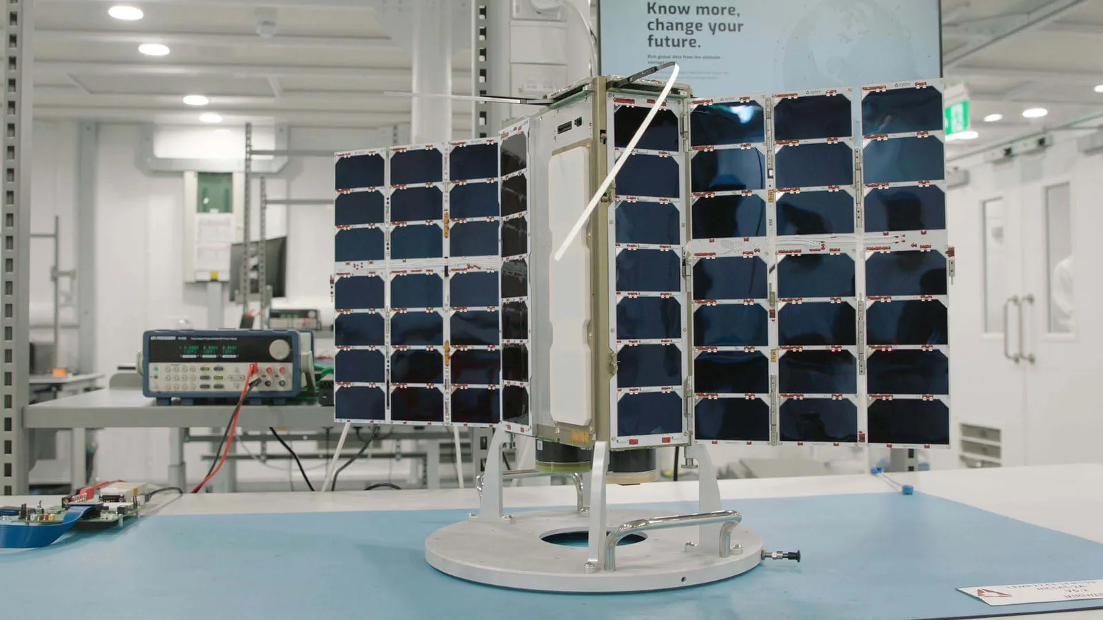 A Spire satellite with deployed solar panels on a test stand in the company's clean room
