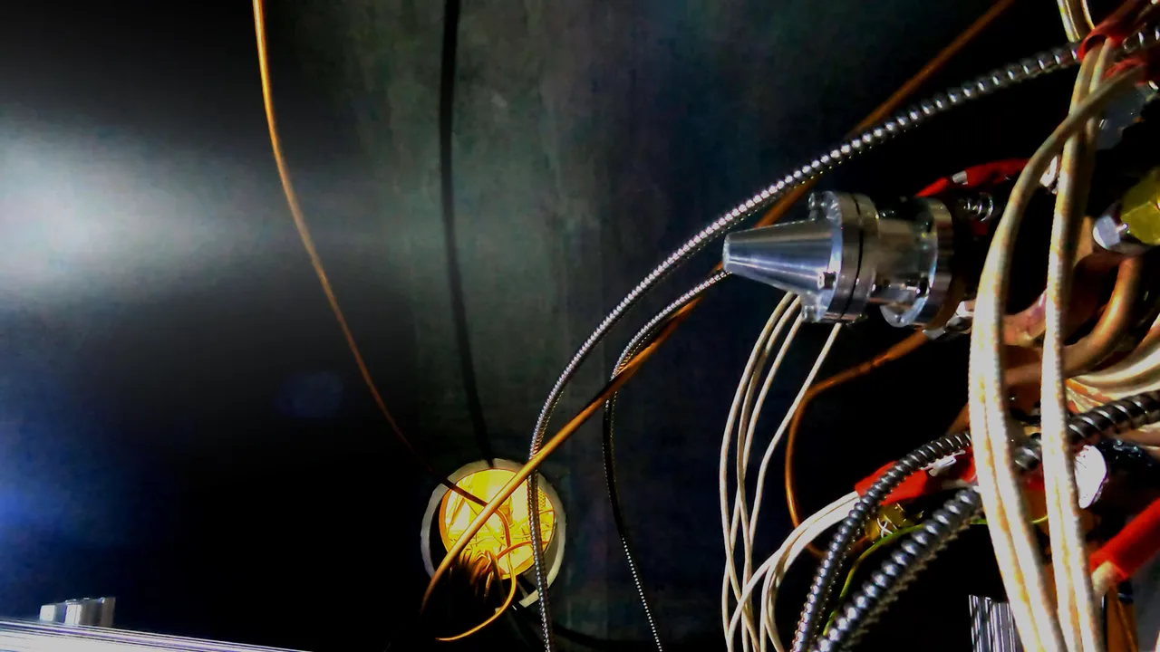 An Omnivore solar thermal thruster firing in a vacuum test chamber, surrounded by propellant lines and wiring