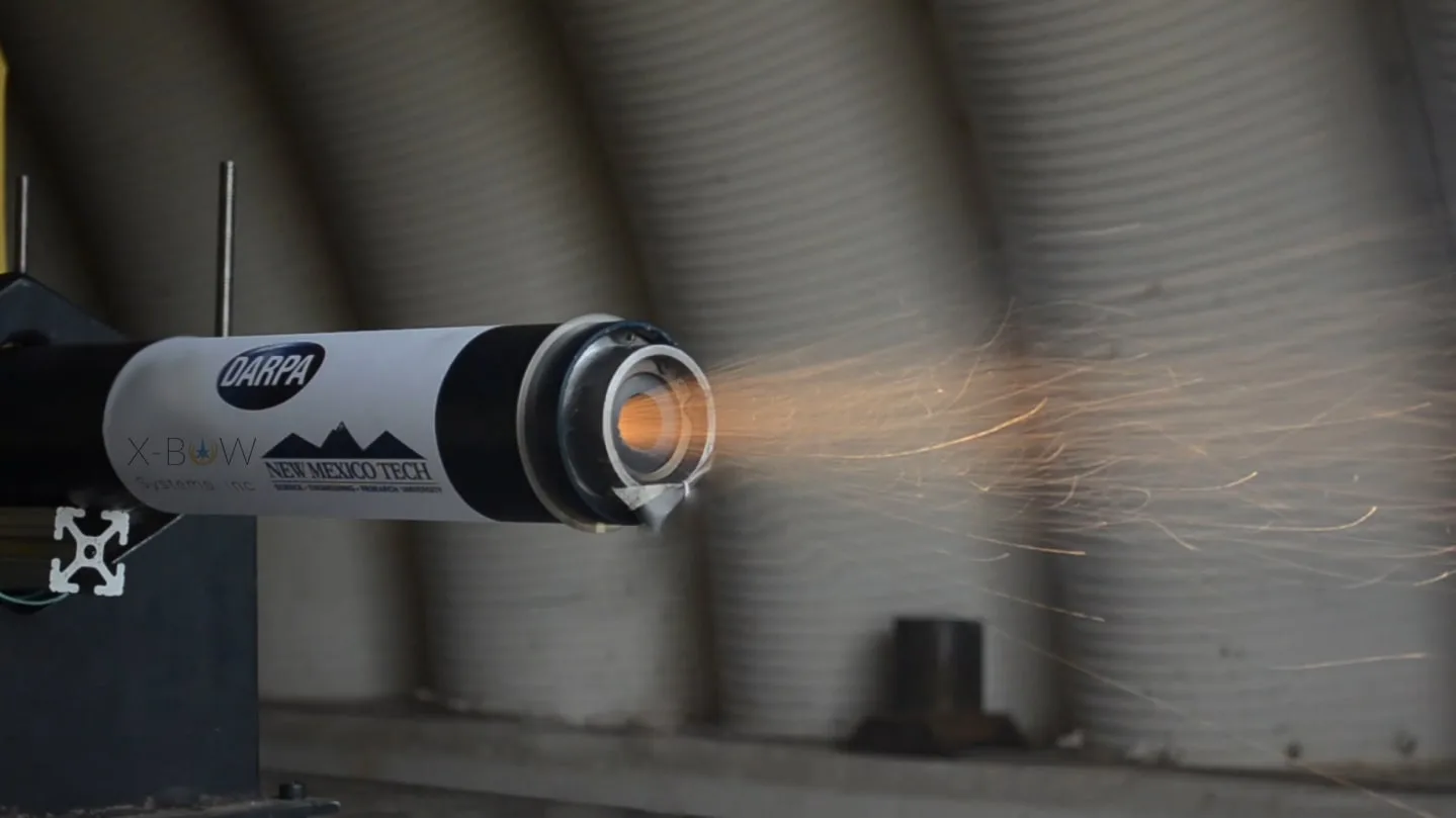 An X-Bow solid rocket motor firing on a horizontal test stand inside a test shelter